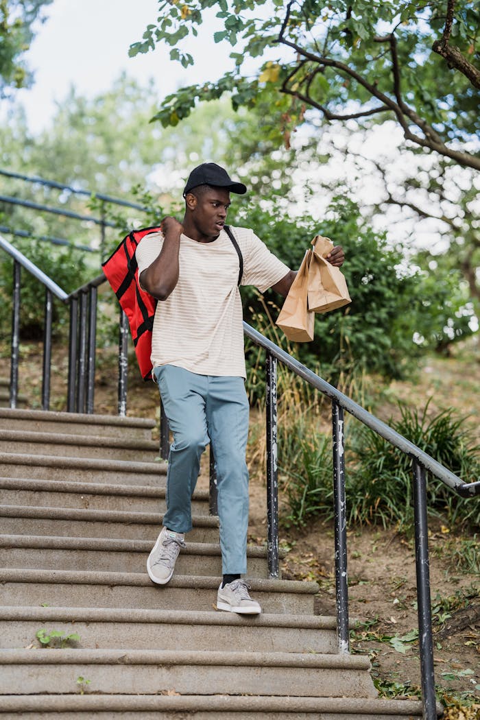 about-us-01 Courier delivering food packages while walking down outdoor steps.